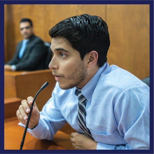 A person speaking into a microphone in a courtroom.